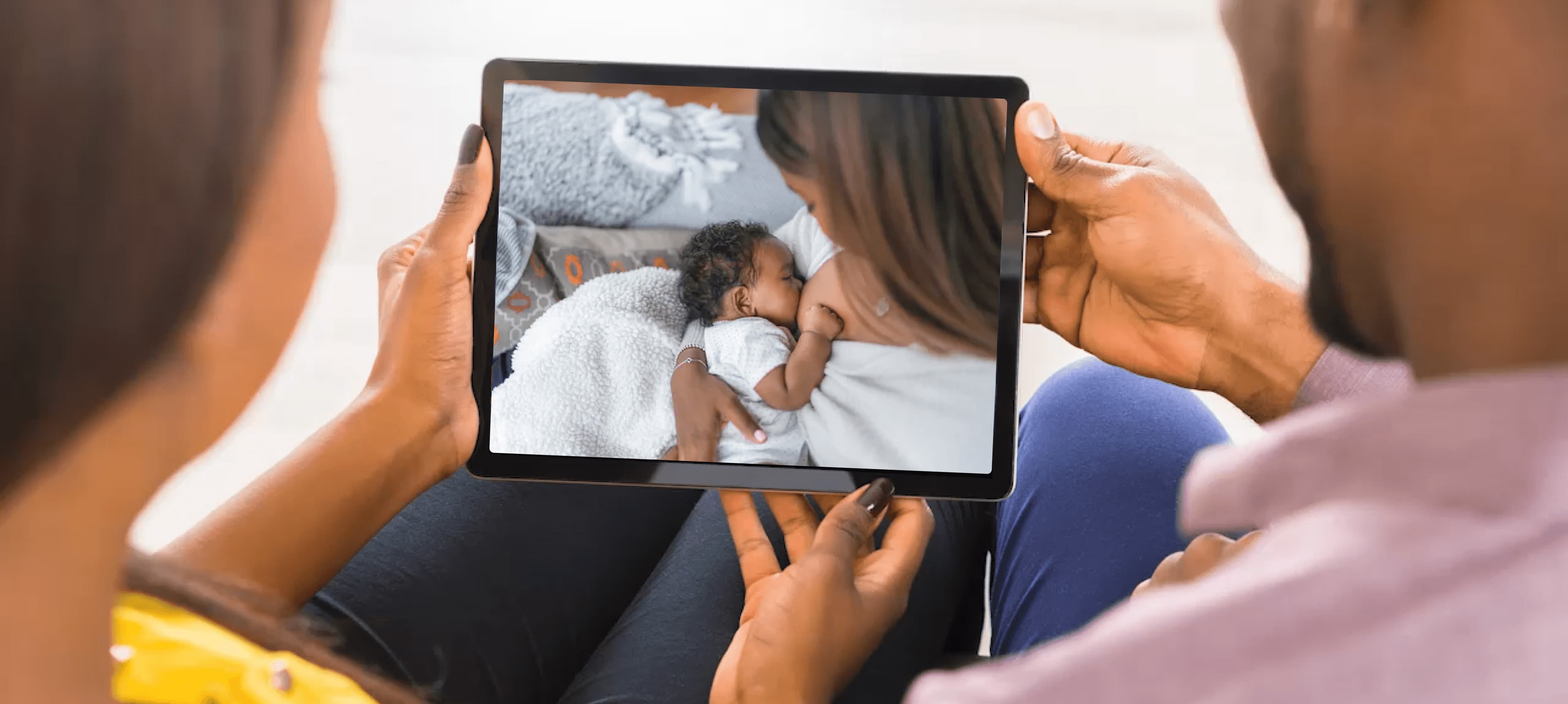 Background. Woman holding baby and watching video on tablet.